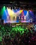 Escenario principal con luces de colores y banda en vivo frente a público animado
