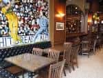 Interior acogedor del Brit's Pub con mesas de madera y decoración temática