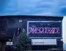 Fachada nocturna de The Masquerade con el cartel iluminado en neón
