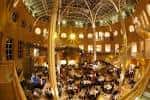 Gran salón del museo decorado para una recepción con mesas redondas y luces cálidas