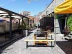 Terraza exterior del venue District con mesas de madera y toldo amarillo