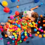 Niños jugando en una piscina de bolas multicolores dentro del museo