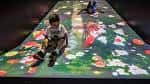 Exhibición interactiva con piso proyectado que muestra flores y mariposas