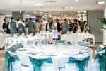 Interior del salón de eventos INOX decorado para una boda con mesas redondas y sillas cubiertas
