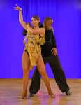 Pareja bailando salsa en un estudio con fondo azul