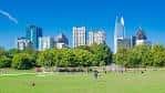 Amplia pradera verde en Piedmont Park con el centro urbano al fondo bajo cielo despejado