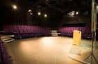 Interior del auditorio del Traverse Theatre con butacas púrpuras dispuestas en semicírculo alrededor de un escenario minimalista