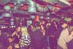Barra y zona de socialización en Dead Wax con clientes conversando y bebidas