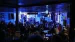 Interior del local durante un evento con iluminación azul y público