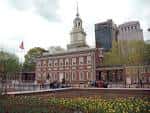 Vista frontal de Independence Hall con bandera estadounidense y jardín de tulipanes en primer plano