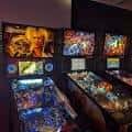 Vista interior del Quarters Arcade Bar mostrando máquinas pinball y juegos de arcade iluminados