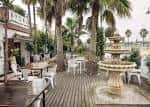 Terraza exterior del restaurante Byoko en Estepona con palmeras y fuente decorativa