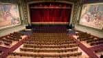 Interior del auditorio de Kingsbury Hall con butacas rojas, escenario y cortinas rojas