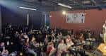 Vista lateral del salón de eventos mostrando el escenario y la audiencia en ambiente nocturno