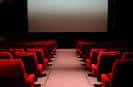Interior del cine con butacas rojas y pantalla grande lista para proyección