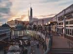Plaza interior de The Gateway al atardecer con mesas y arquitectura moderna