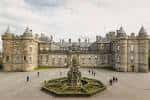 Vista frontal del Palacio de Holyroodhouse con fuente central y jardines