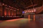Escenario vacío del auditorio con iluminación cálida y cortinas rojas