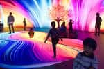 Interior interactivo del museo con proyecciones de luz y visitantes disfrutando la experiencia