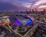 Panorámica nocturna del estadio iluminado con luces de colores y skyline de Atlanta al fondo