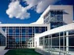 Fachada moderna del edificio con grandes ventanales y cielo azul