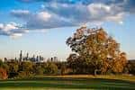 Paisaje otoñal en Fairmount Park con árboles dorados y skyline urbano al horizonte