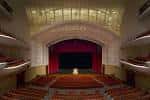 Interior del auditorio mostrando el escenario con cortinas rojas y butacas