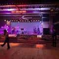 Escenario interior con banda tocando en vivo durante evento nocturno