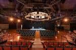 Interior del teatro con butacas rojas y gran lámpara central