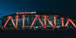 Fachada nocturna del State Farm Arena iluminada en naranja con el nombre 'ATLANTA' proyectado