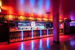 Interior del Club Tropicana con barra iluminada y luces de neón