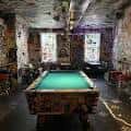 Sala interior con mesa de billar y paredes decoradas con arte urbano