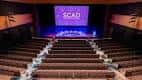 Interior del auditorio con escenario y pantalla de proyección