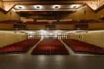 Interior del auditorio con butacas rojas y escenario