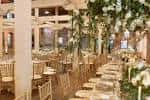 Interior del salón de eventos decorado con flores blancas y mesas dispuestas para una celebración