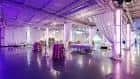 Salón principal preparado para evento con mesas cubiertas y cortinas blancas decorativas