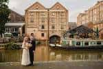 Pareja de novios frente al Canalhouse en Nottingham con barcos y arquitectura histórica al fondo
