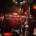 Interior del local con decoración en tonos rojos, lámparas colgantes y ambiente íntimo