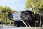 Fachada principal del Palau de Vidre rodeado de árboles en un día soleado