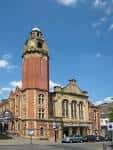 Vista exterior del Victoria Hall en Sheffield con su característica torre de ladrillo rojo bajo un cielo azul
