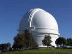 Vista exterior del domo blanco del Observatorio Palomar bajo un cielo azul despejado