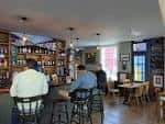 Interior acogedor del pub Constant Service, mostrando barra, estanterías de bebidas y zona de mesas