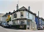 Fachada exterior del pub Constant Service en Brighton, con arquitectura tradicional y detalles blancos
