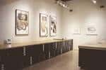 Galería de exposiciones con obras de grabado enmarcadas y estanterías oscuras