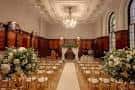 Interior del salón principal decorado para una boda con arreglos florales y sillas doradas