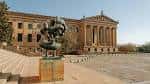 Fachada lateral del museo con escultura moderna en primer plano y plaza despejada ideal para eventos