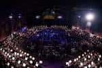 Vista panorámica del auditorio durante un evento con iluminación escénica y público sentado