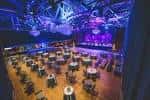 Configuración de sala para eventos con mesas redondas y luces ambientales