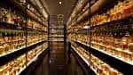 Interior con estanterías iluminadas llenas de botellas de whisky