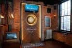 Interior del pub con decoración de ladrillo y un reloj de dardos iluminado